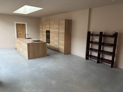 Moderne keuken met houten kasten en een betonnen vloer, ruime indeling.